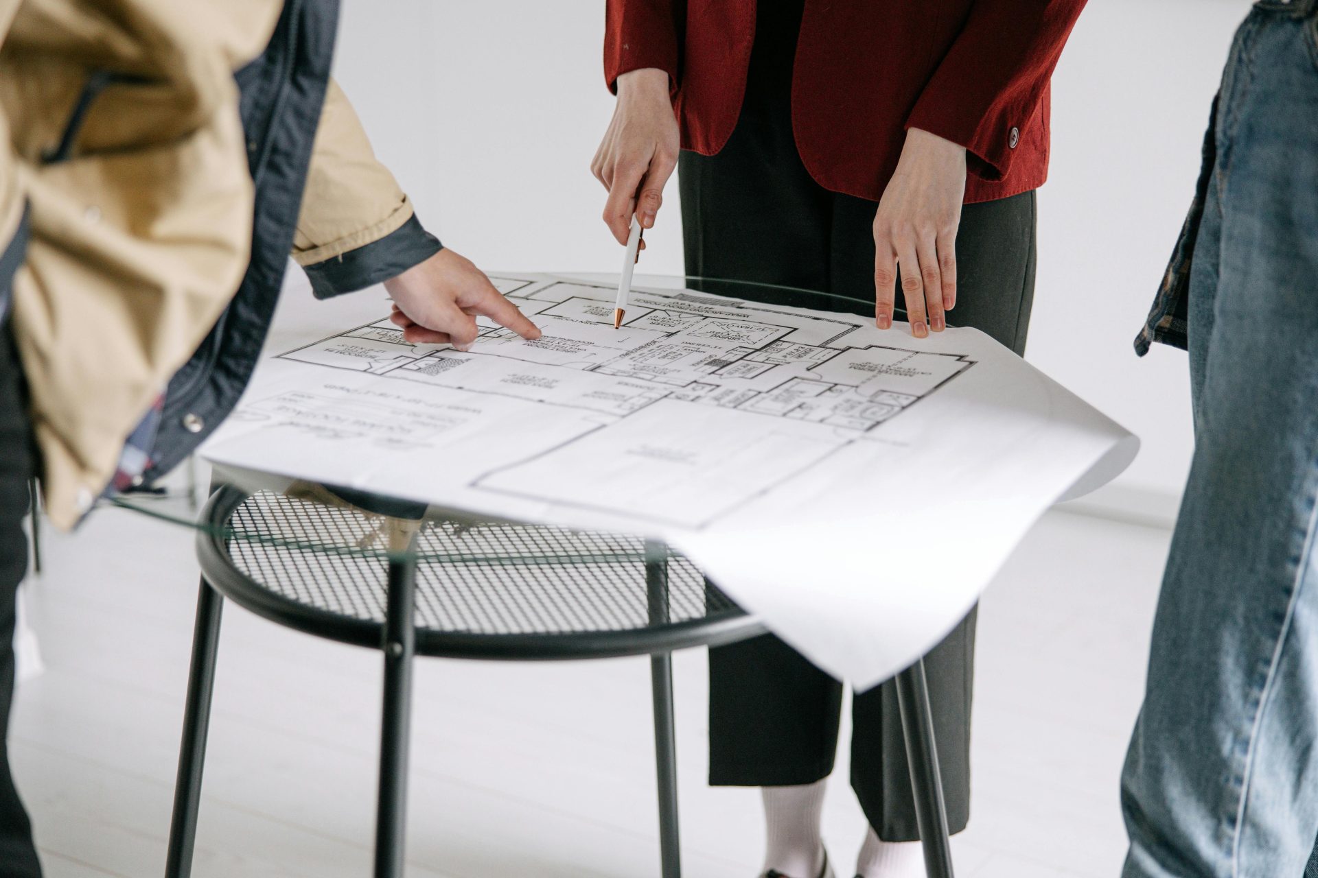 Un groupe de personnes examinant des plans architecturaux sur une table à l'intérieur.